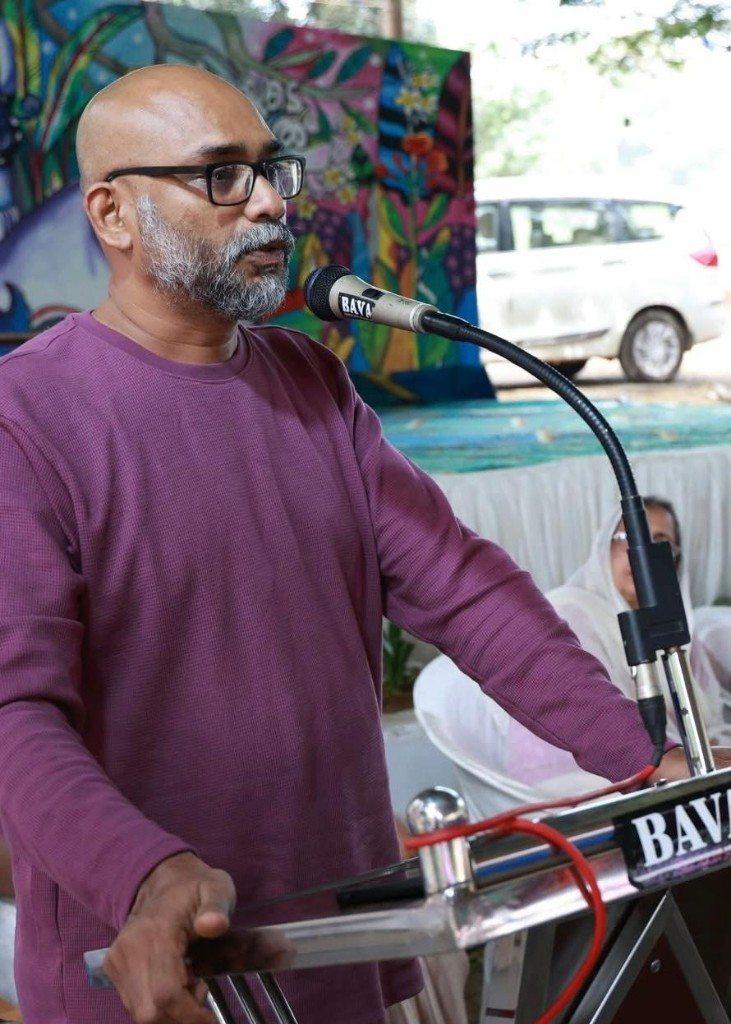 O.P. Suresh speaking at a microphone. The stand reads BAVA.